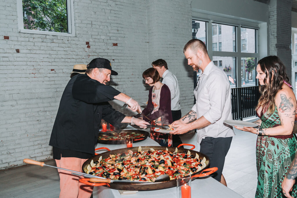 Guests standing in line for paealla at a wedding at THE 101 in Seattle