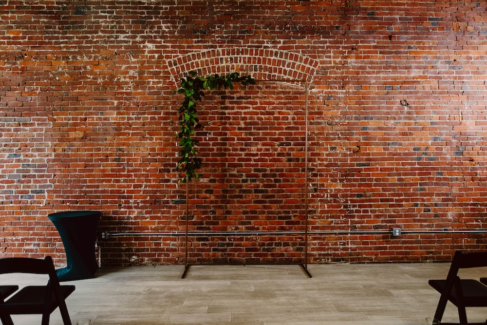 Wedding ceremony backdrop at THE 101 against a red brick wall