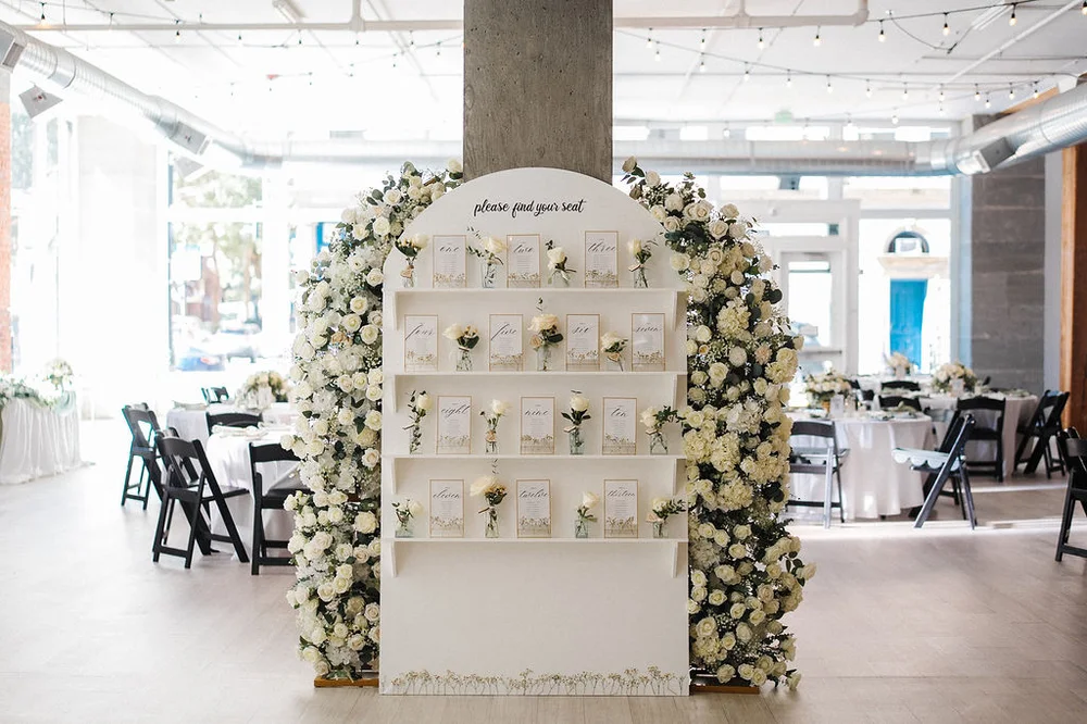 Wedding seating chart surrounded by white floral arrangements at THE 101 Seattle