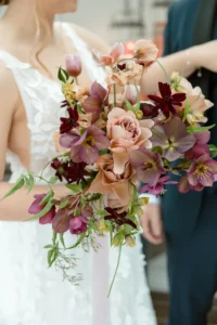 Bride holding a bouquet with hellebore, big burgundy flowers